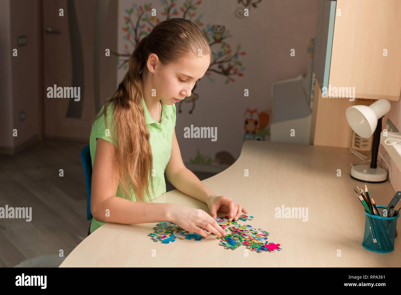 Cute little girl solving puzzle together sitting at the table Stock Photo