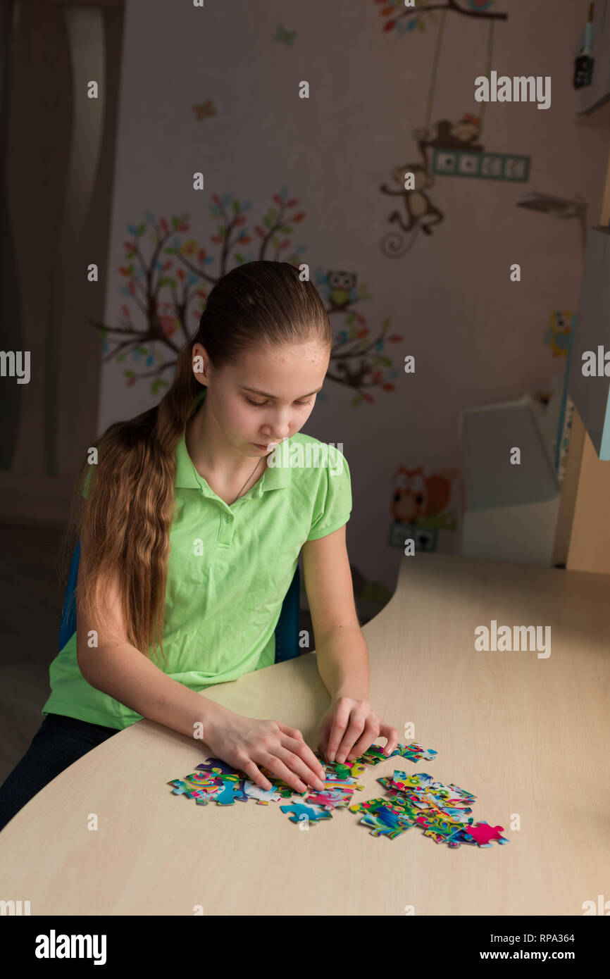 Cute little girl solving puzzle together sitting at the table Stock Photo