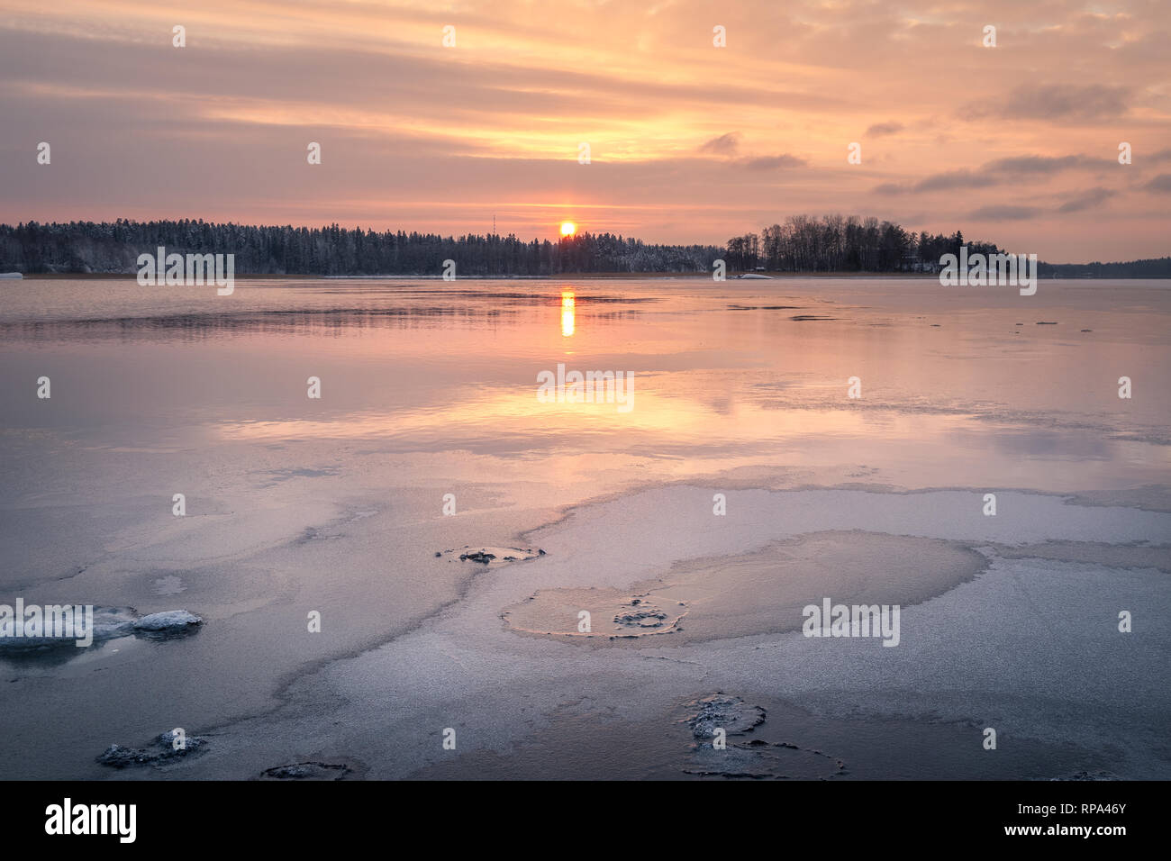Scenic winter landscape with sunset and water reflections at evening time in Finland Stock Photo