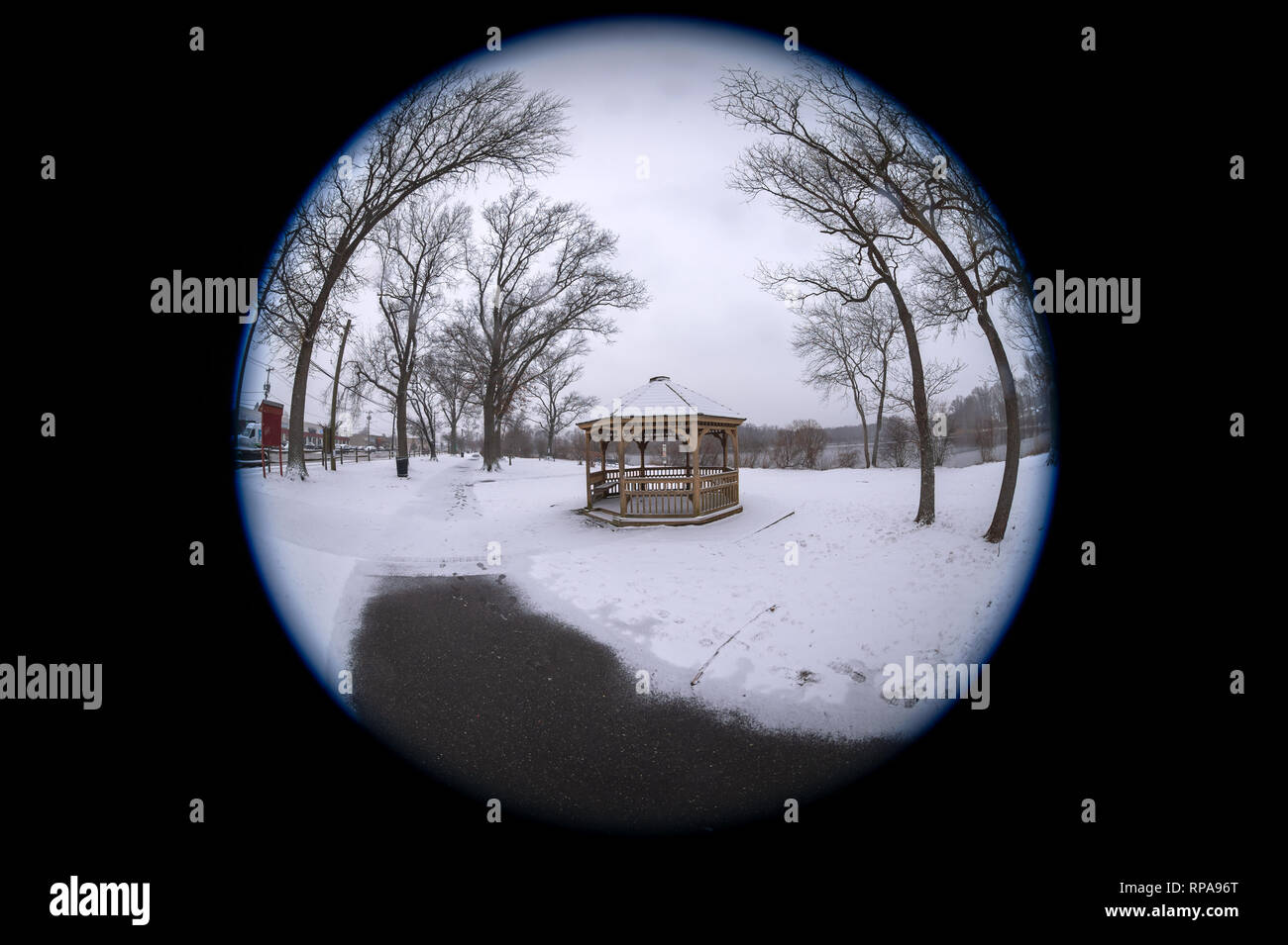 Long Island, New York, USA. 20th Feb, 2019. Snow falls at Mill Pond Park, with path partly plowed clear leading to wood gazebo and bare trees, on Long Island. 180 degree fisheye view of Nassau County public park. Credit: Ann E Parry/Alamy Live News Stock Photo