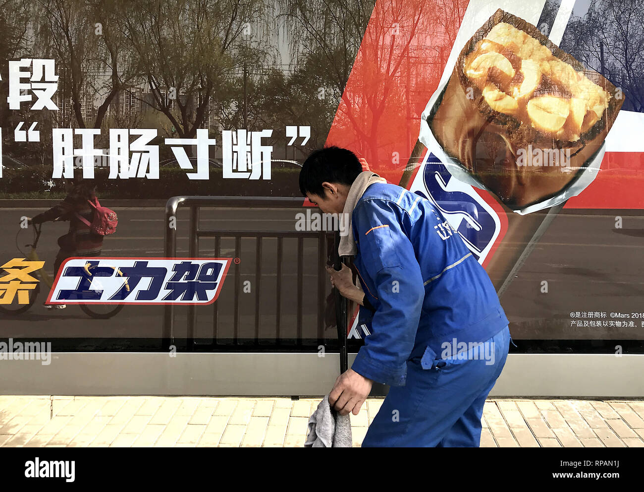 April 11, 2018 - Beijing, China - A Chinese worker cleans a sign advertising American Snicker bars in Beijing on April 11, 2018.  Chinese President Xi Jinping promised today to open China's economy even further for foreign investments and lower tariffs on foreign automobiles in hopes of avoiding a trade war the the U.S.. (Credit Image: © Todd Lee/ZUMAprilESS.com/ZUMA Wire) Stock Photo