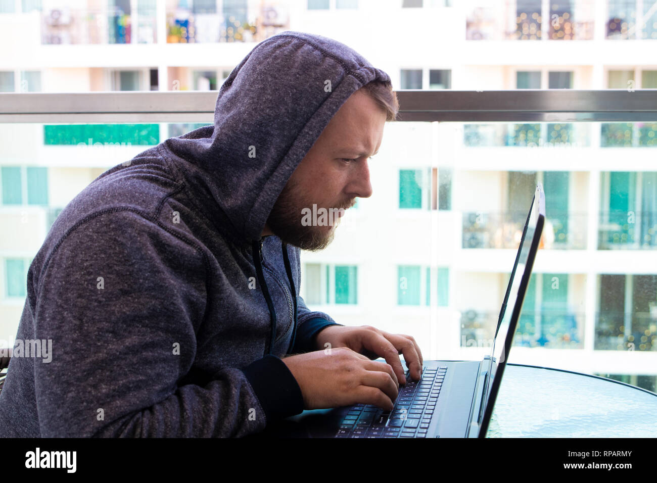 Cybercrime, hacking and technology concept - male hacker writing code or using computer virus program for cyber attack Stock Photo