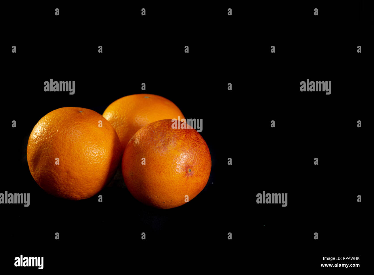 Three red oranges on a black background - image Stock Photo
