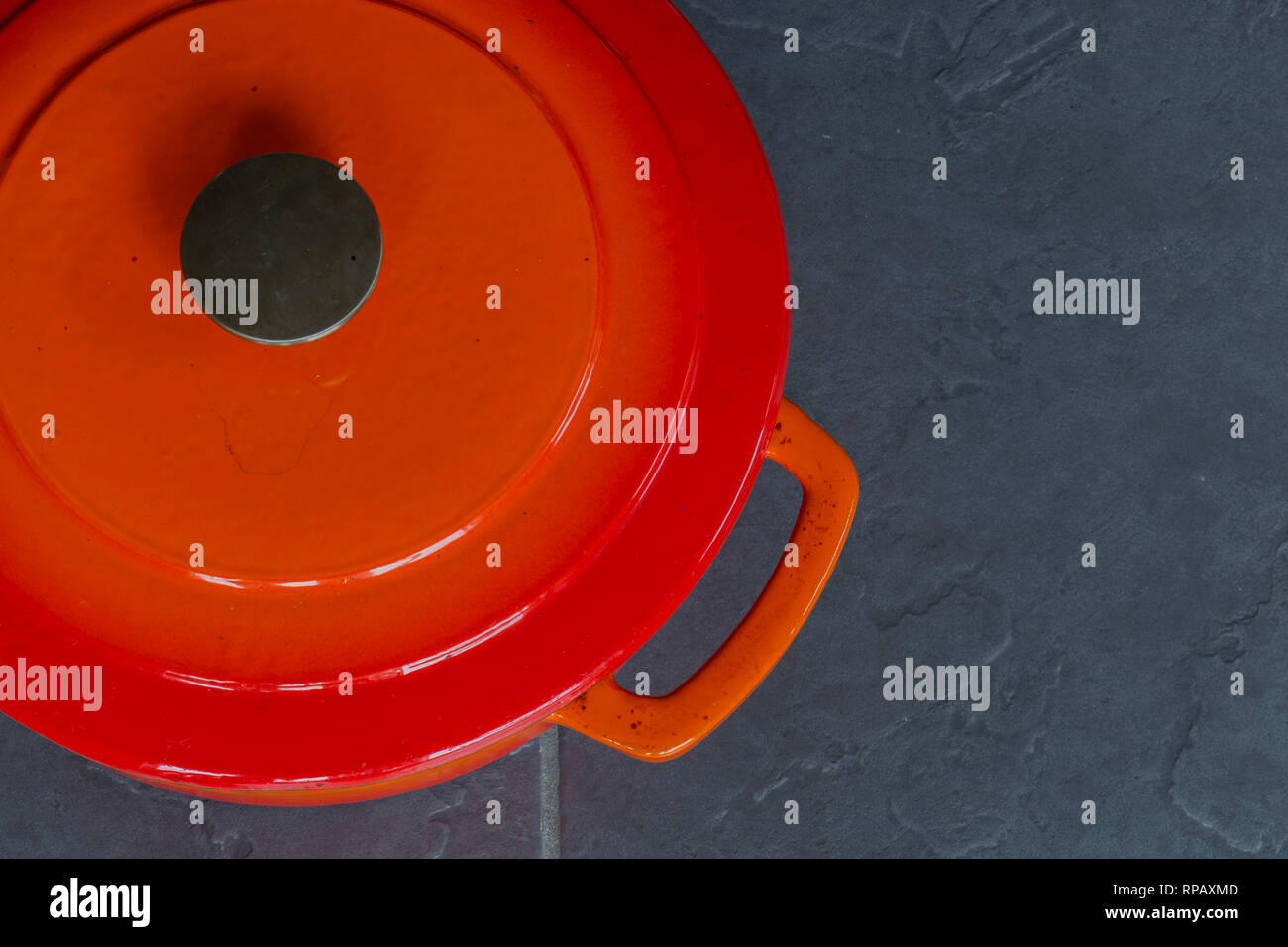 Orange traditional ceramic roasting dish with lid on a grey tile kitchen worktop Stock Photo