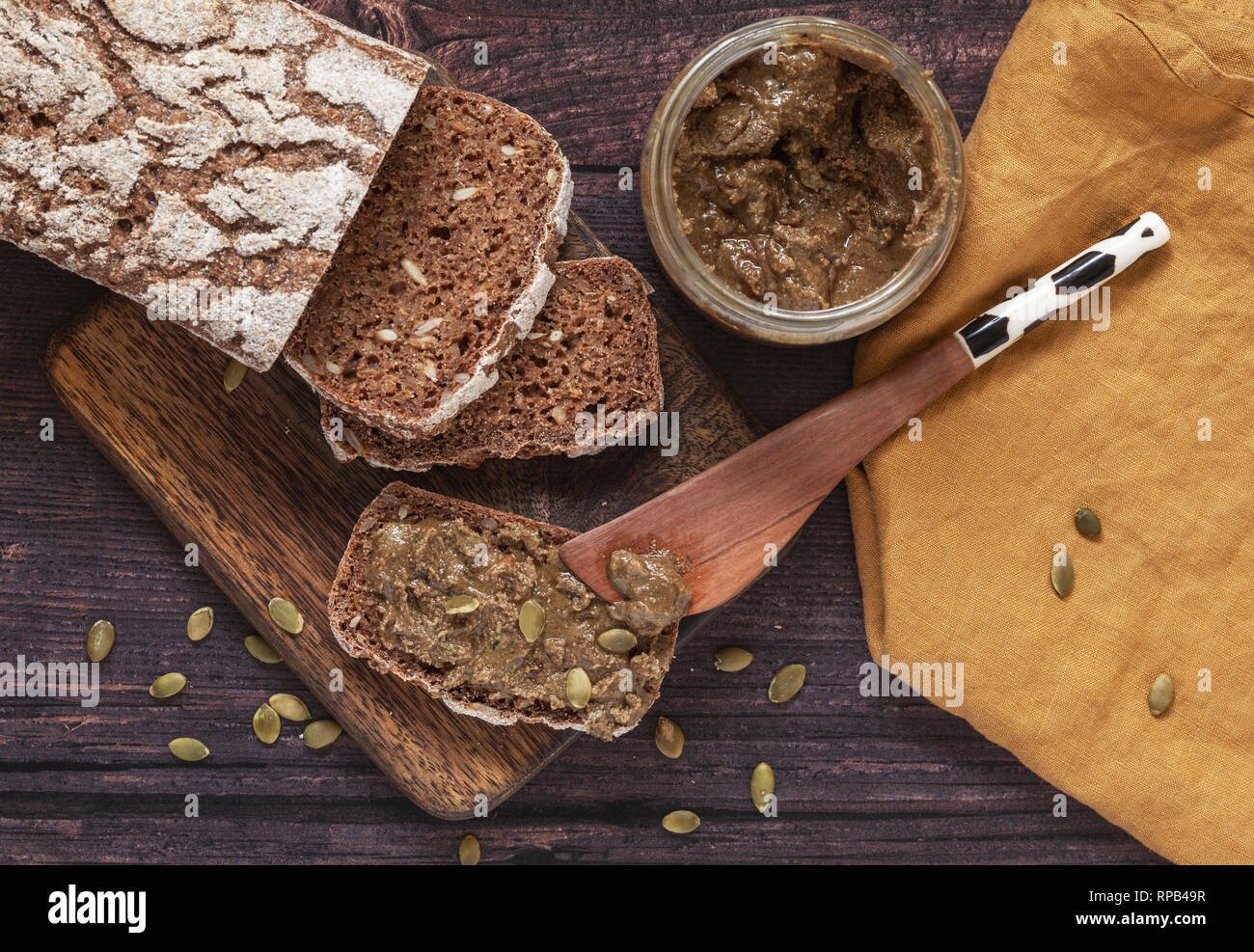 Homemade rye bread with homemade pumpkin seed spread on wooden breadboard Stock Photo