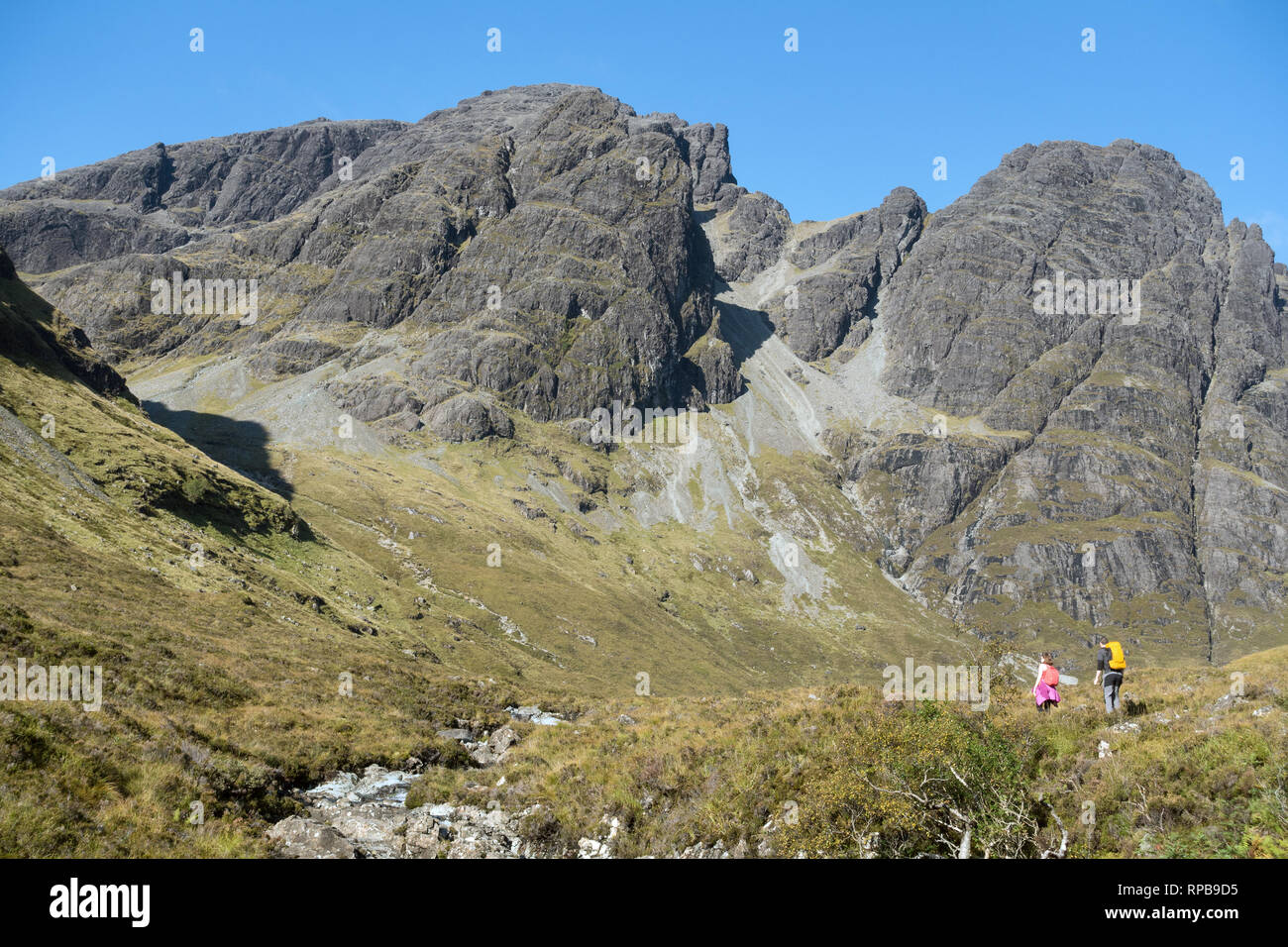Two hill walkers below Bla Bheinn (centre) and Clach Glas (right) in the Black Cuillin Mountains on the Isle of Skye, Scotland, UK Stock Photo