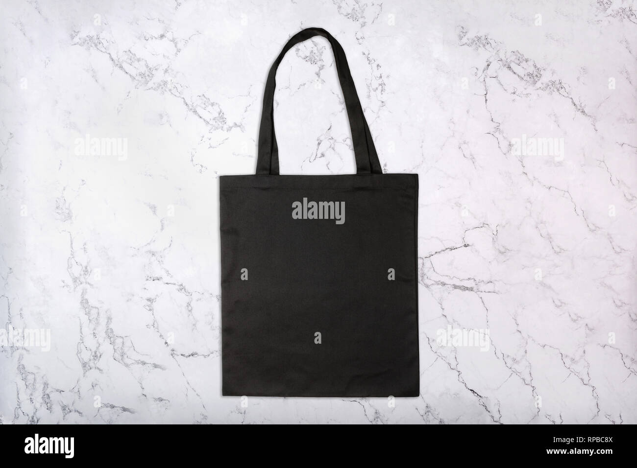 Black shopping bag on marble background with natural pattern Stock Photo