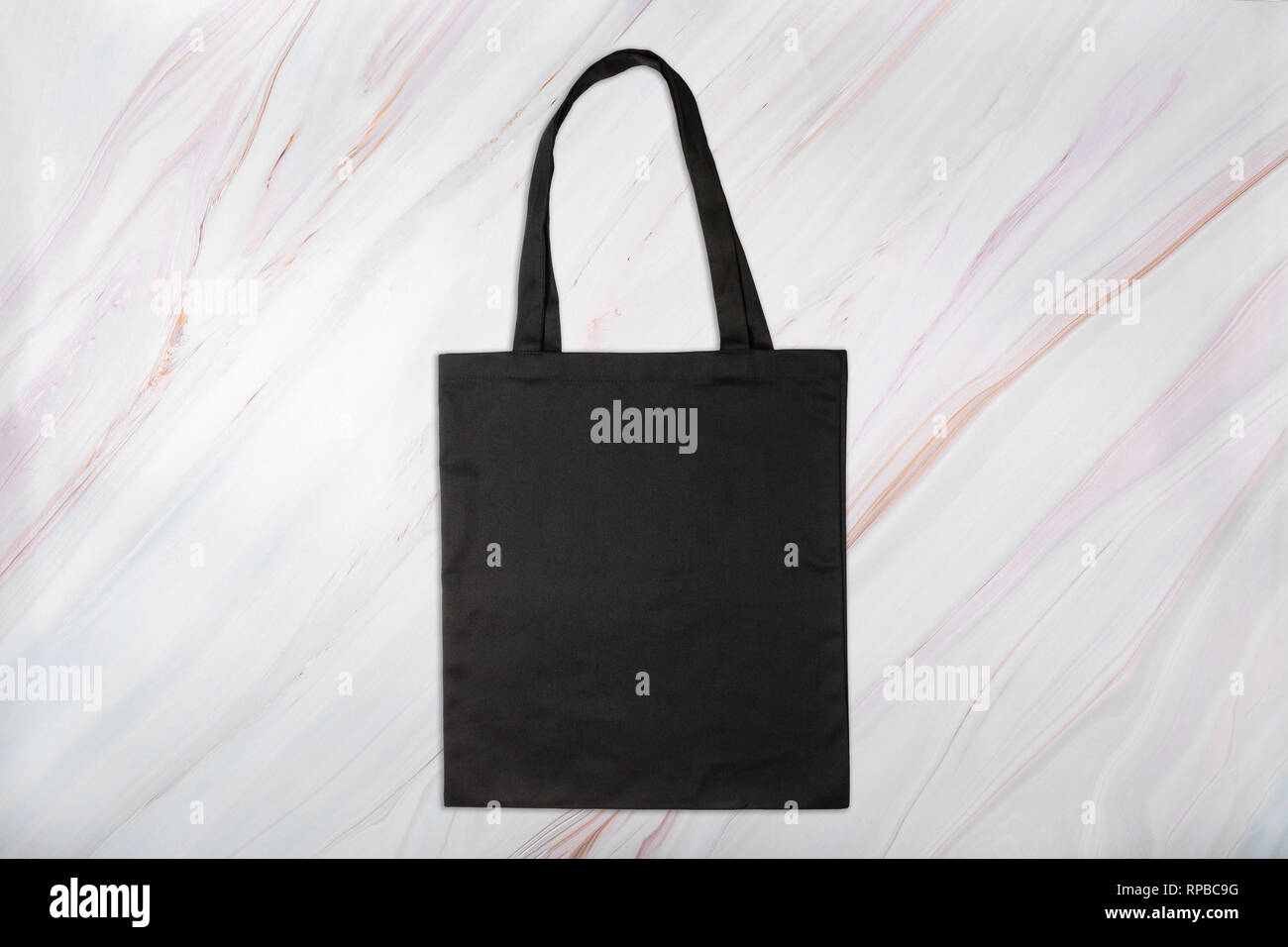 Black shopping bag on marble background with natural pattern Stock Photo