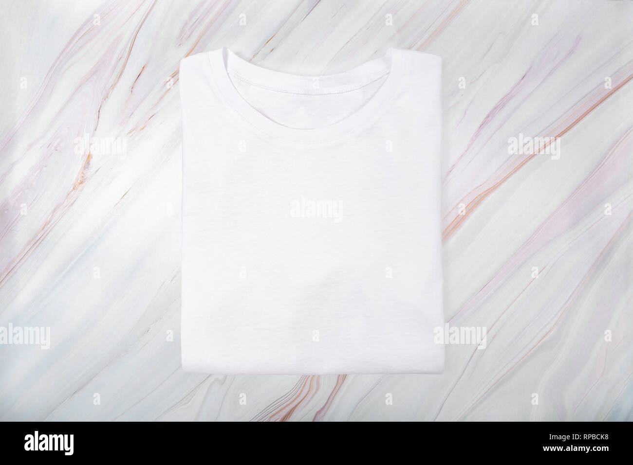 White folded t-shirt on white marble background. Identity template Stock Photo