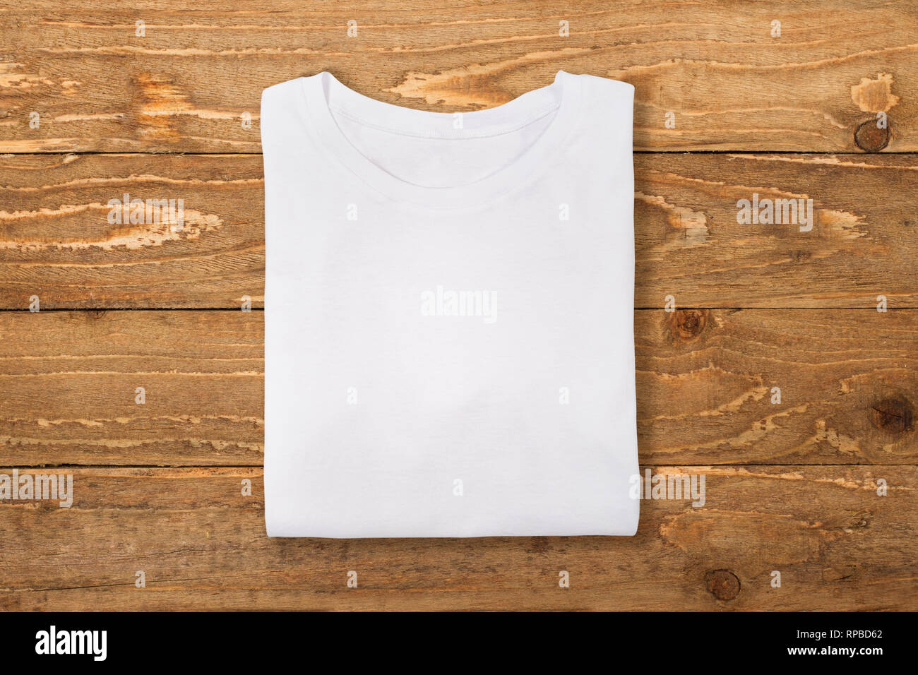 White folded t-shirt on wooden wall background. Flat lay Stock Photo