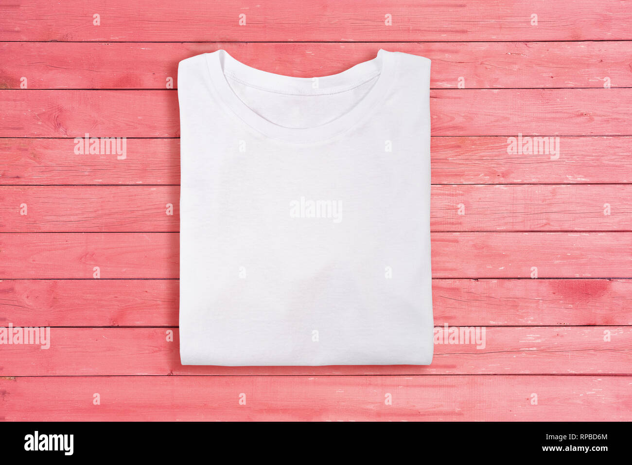Above view of white folded blank t-shirt on pink wooden background. Female tshirt design template Stock Photo
