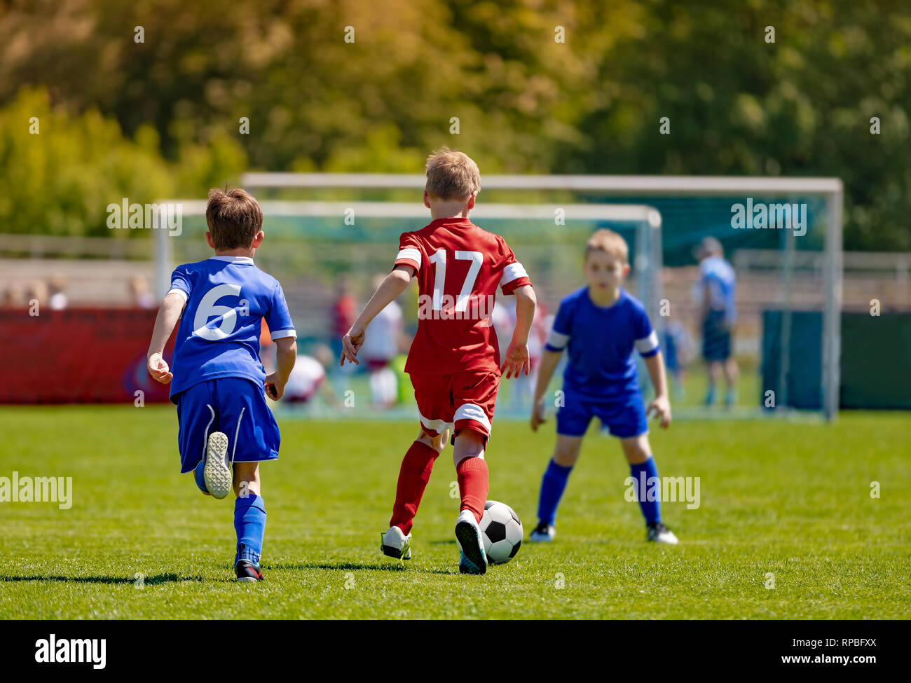 Footballers Kicking Football Match. Soccer School Tournament Game. Kids in Red and Blue Sports Jerseys. Young Soccer Players Running After the Ball. S Stock Photo