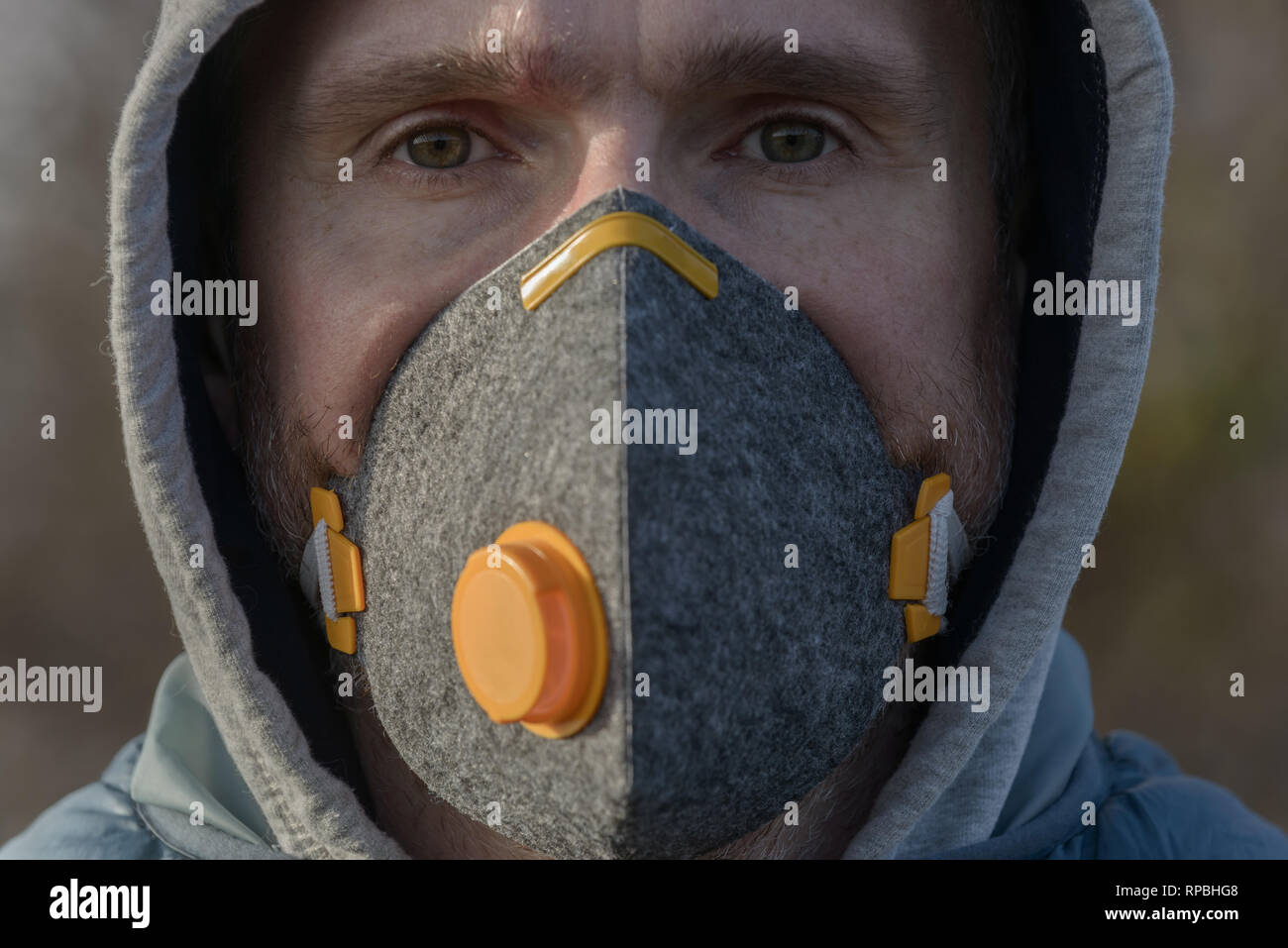 man wearing a real anti-pollution, anti-smog and viruses face mask; dense smog in air Stock Photo