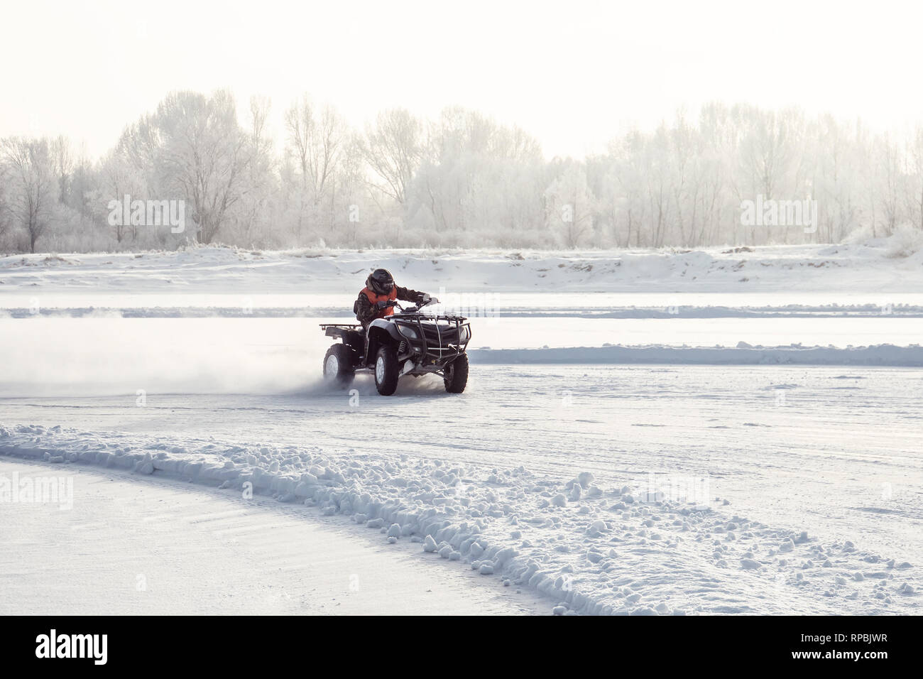 extreme winter motocross. The driver of the ATV skidded on the turn on a steep road. The ATV rider rides on the frozen ice on the lake Stock Photo