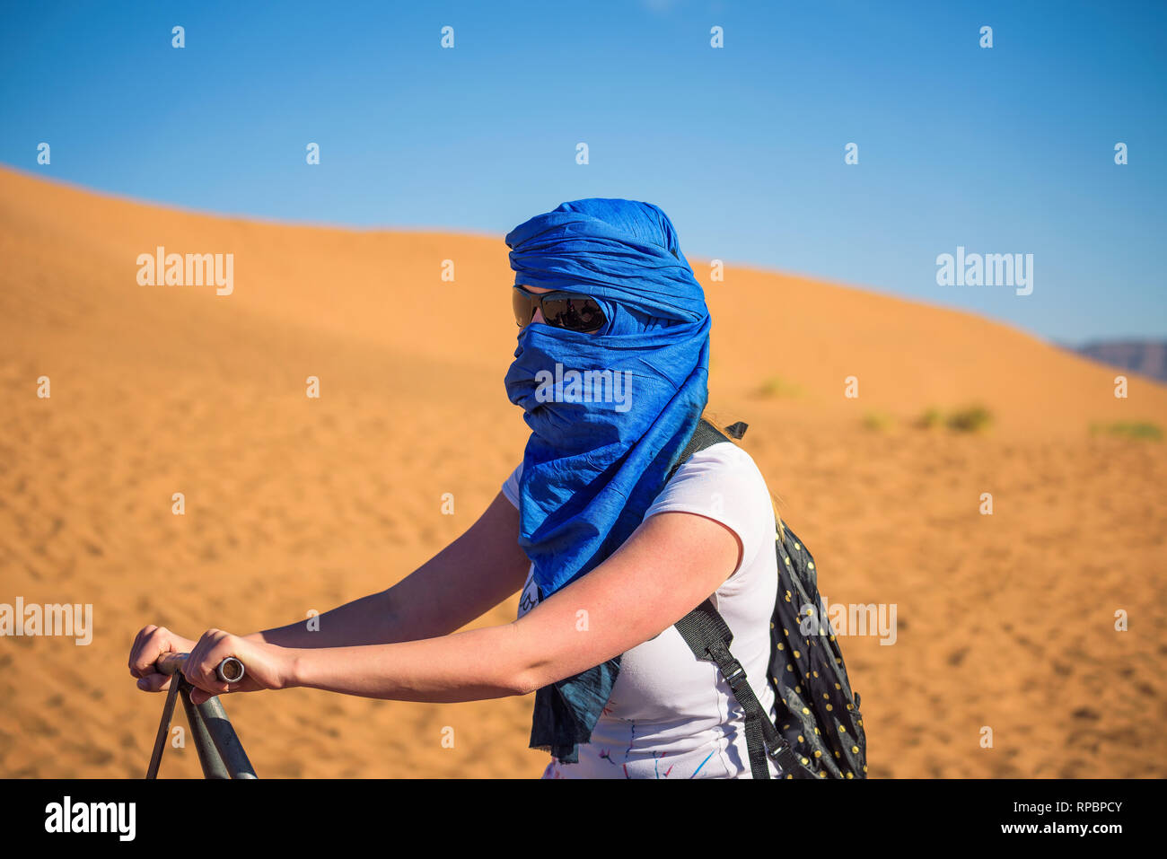 Tourist rides a camel through the sand dunes in the Sahara desert Stock Photo