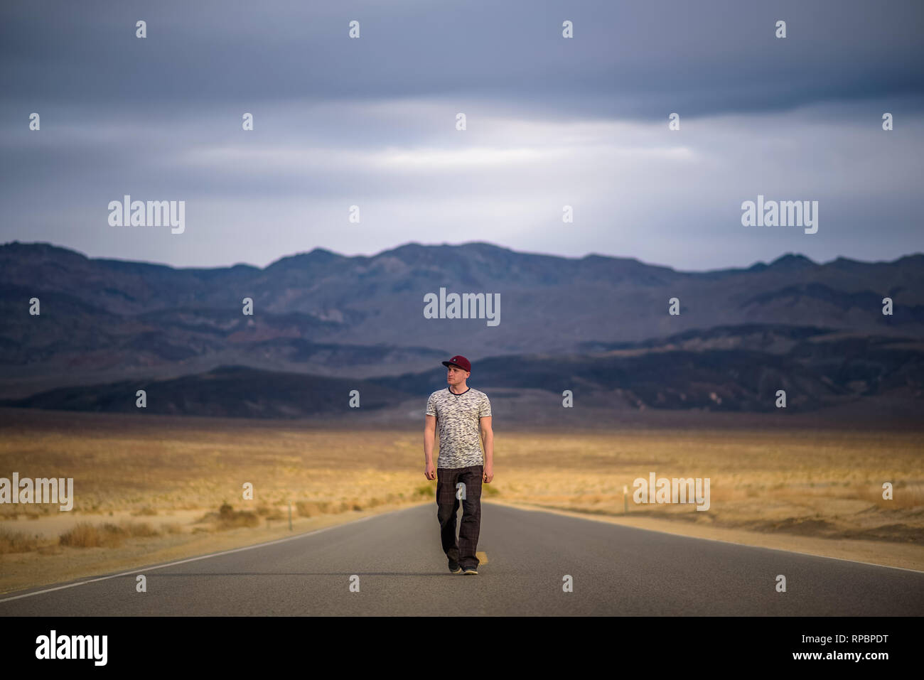 Young man walking alone through an empty street in the desert of Death Valley Stock Photo