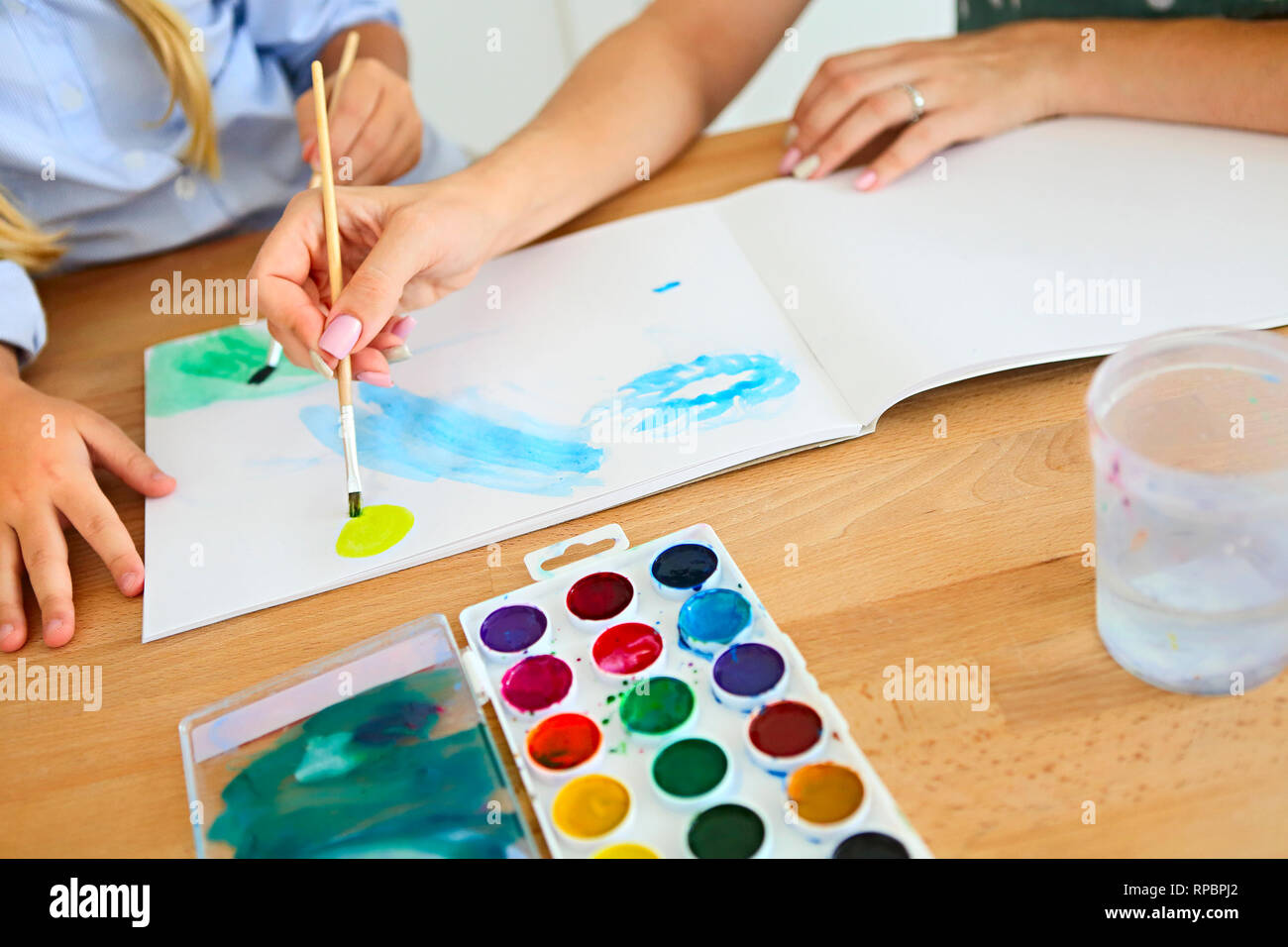 Mother and daughter painting together at home on the kitchen with ...