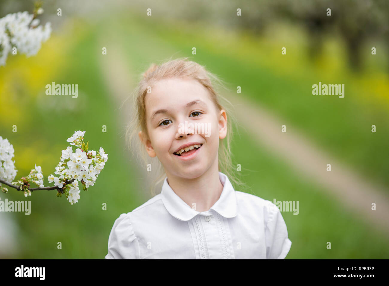 Happy Female Kid With Blonde Hair And Blowm Eyes In The Light Coat