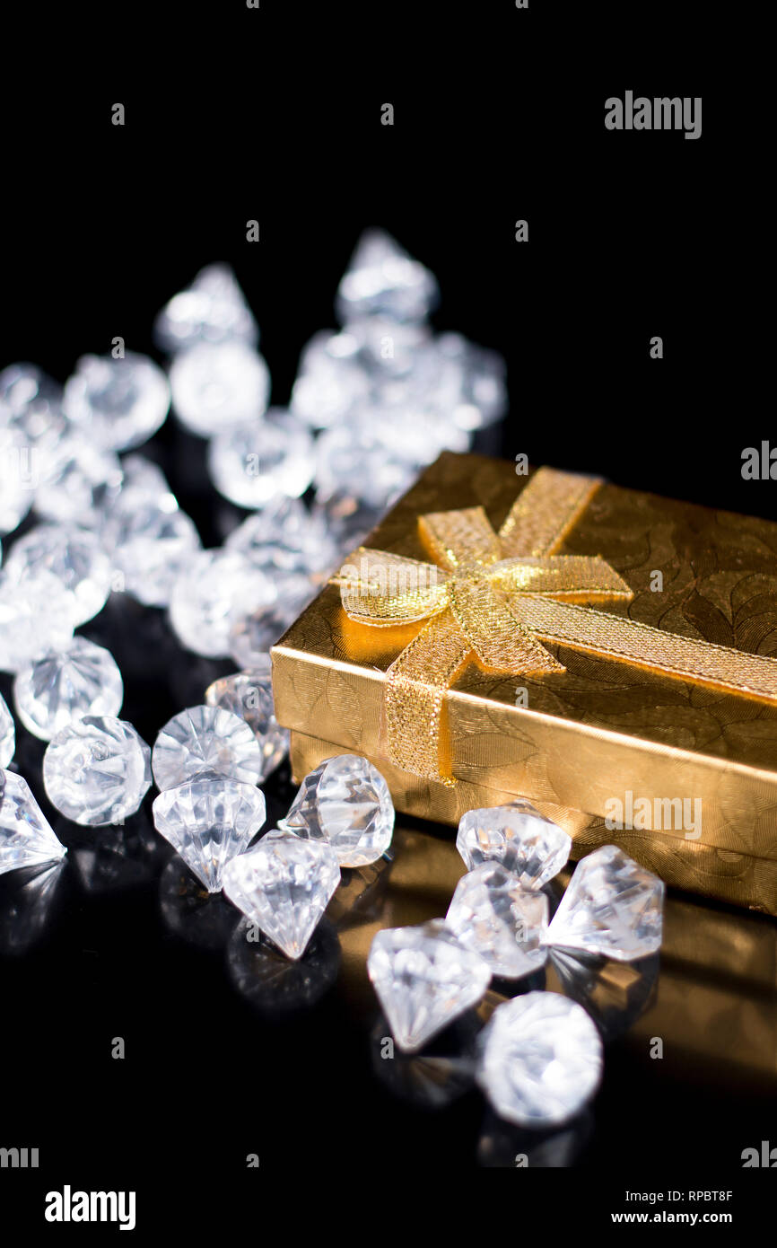 Golden jewellery box with shiny diamonds on a black glossy background
