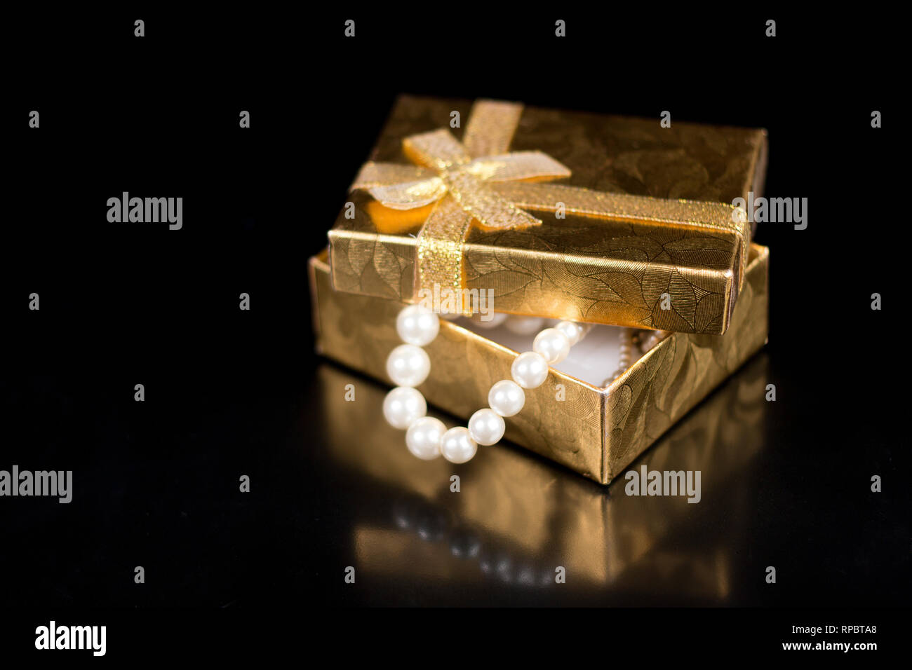 Golden jewellery box with shiny pearls on a black glossy background Stock  Photo - Alamy