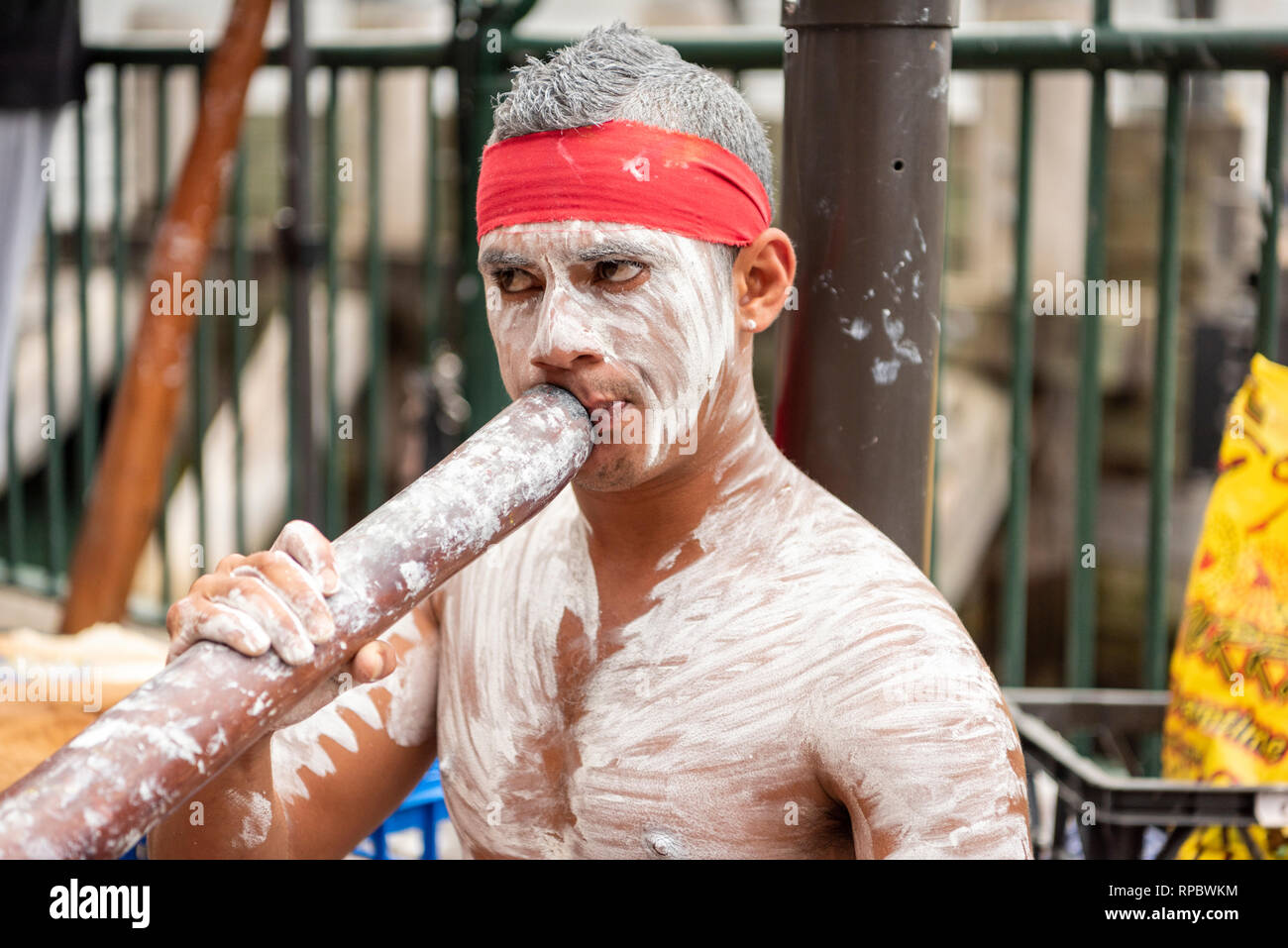 A busker playing a digeridoo in Sydney Australia painted in white aboriginal body make up Stock Photo