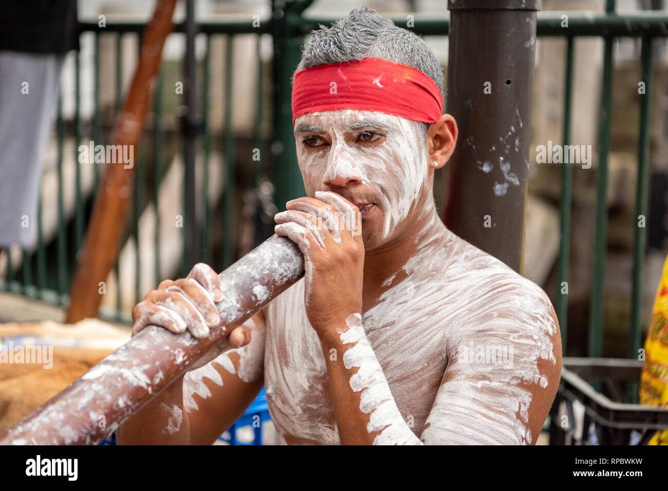 A busker playing a digeridoo in Sydney Australia painted in white aboriginal body make up Stock Photo