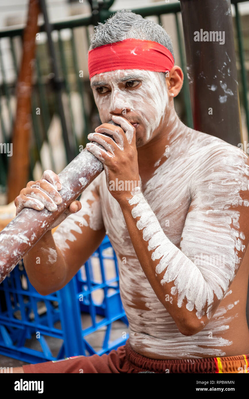 A busker playing a digeridoo in Sydney Australia painted in white aboriginal body make up Stock Photo