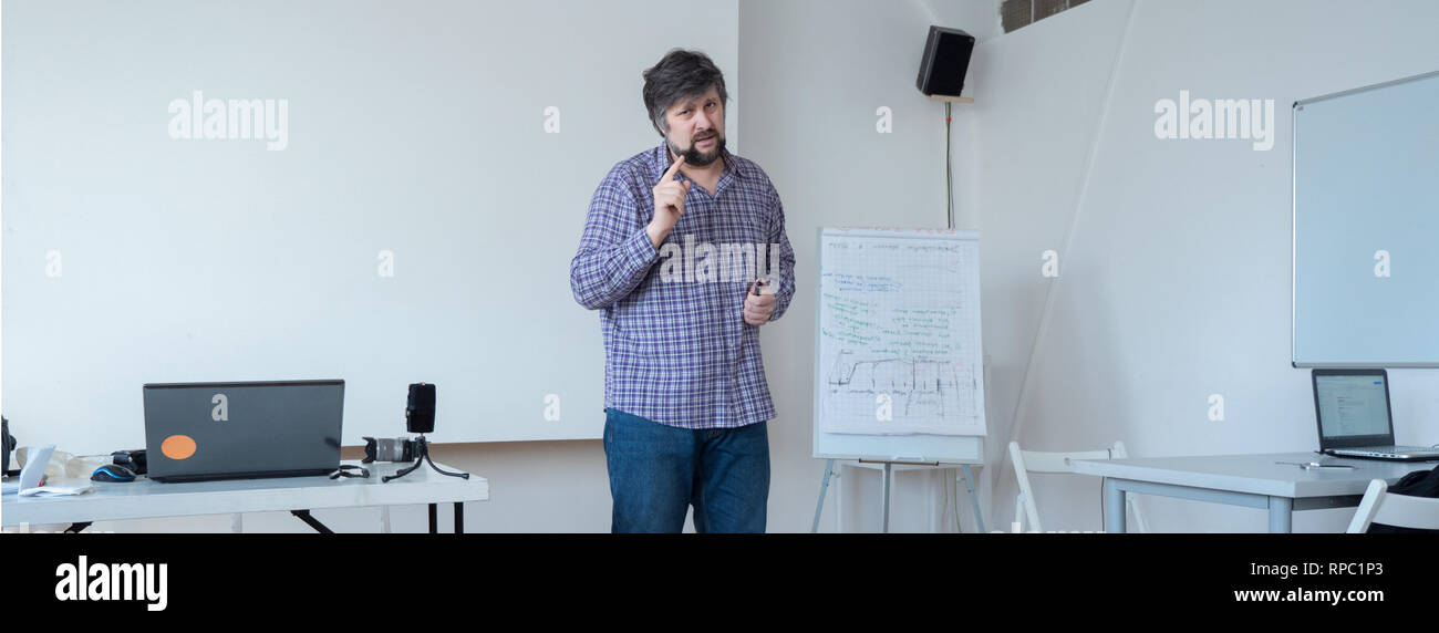 Male with beard and mustache in classroom. Project presentation. Startup presenting background. Speaking to audience in classroom, lecturing hall Stock Photo