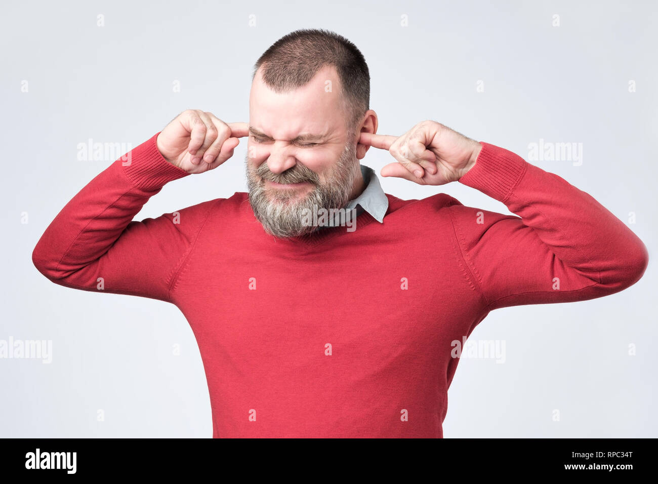 Senior man, covering closed ears annoyed by loud noise not wanting to hear story Stock Photo