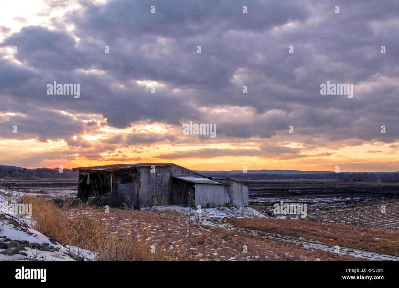 Amazing winter sunset over humble shanty and farmlands in the black