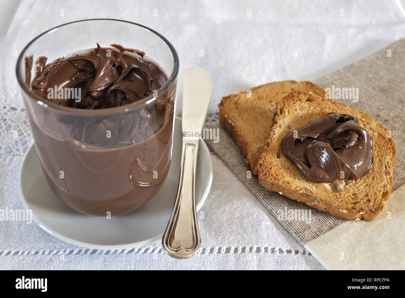 fette biscottate con crema di nocciole al cacao con bicchiere Stock Photo