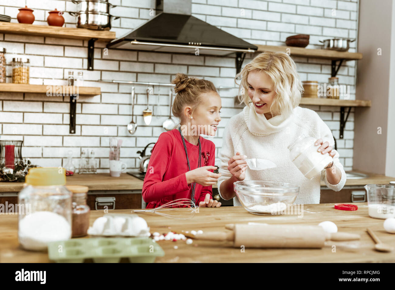 Educated woman with wavy hairs showing her curious daughter Stock Photo