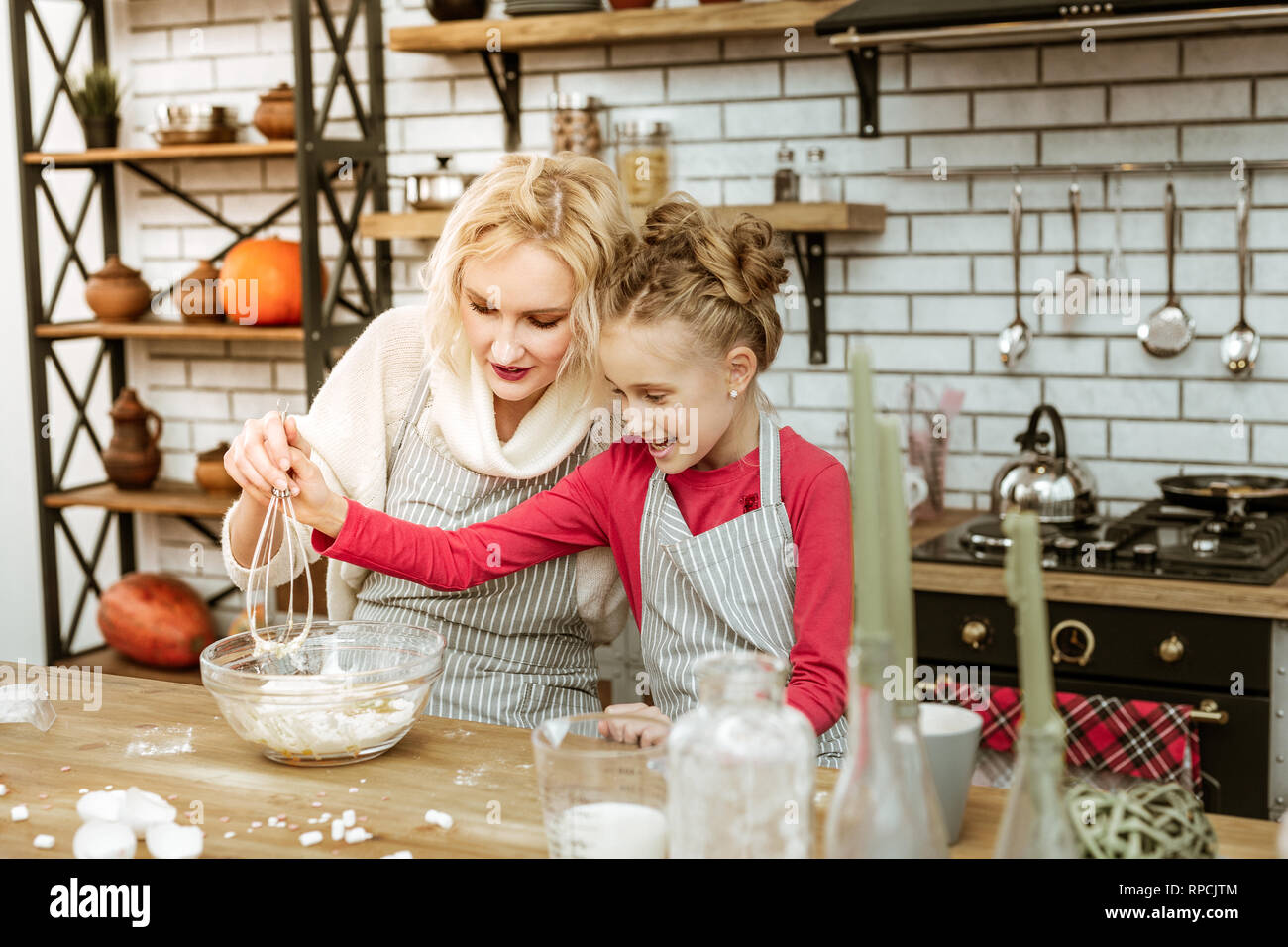 Light-haired smiling child taking metal whisk for connecting ingredients Stock Photo