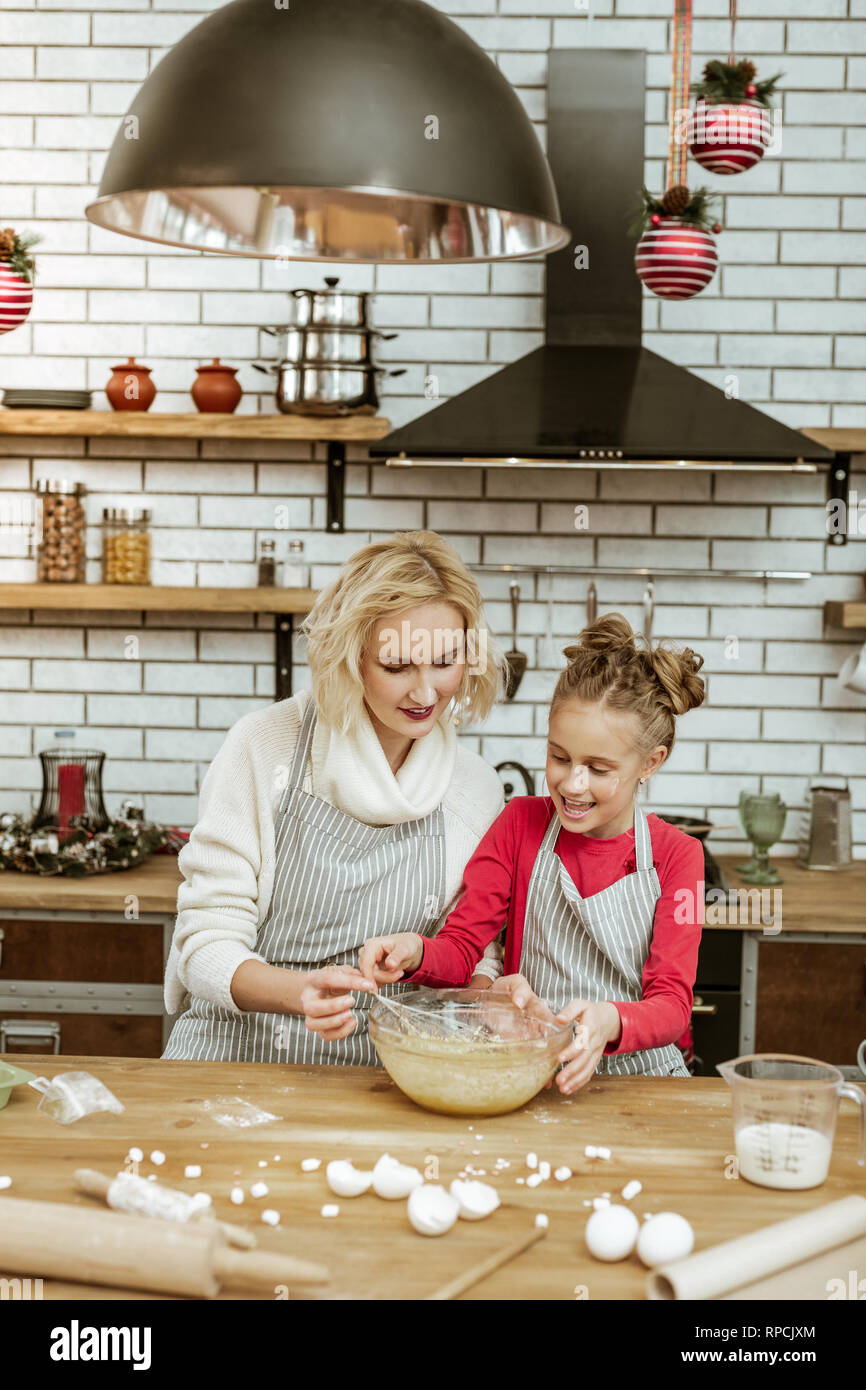 Accurate appealing adult lady in white sweater transmitting whisk Stock Photo