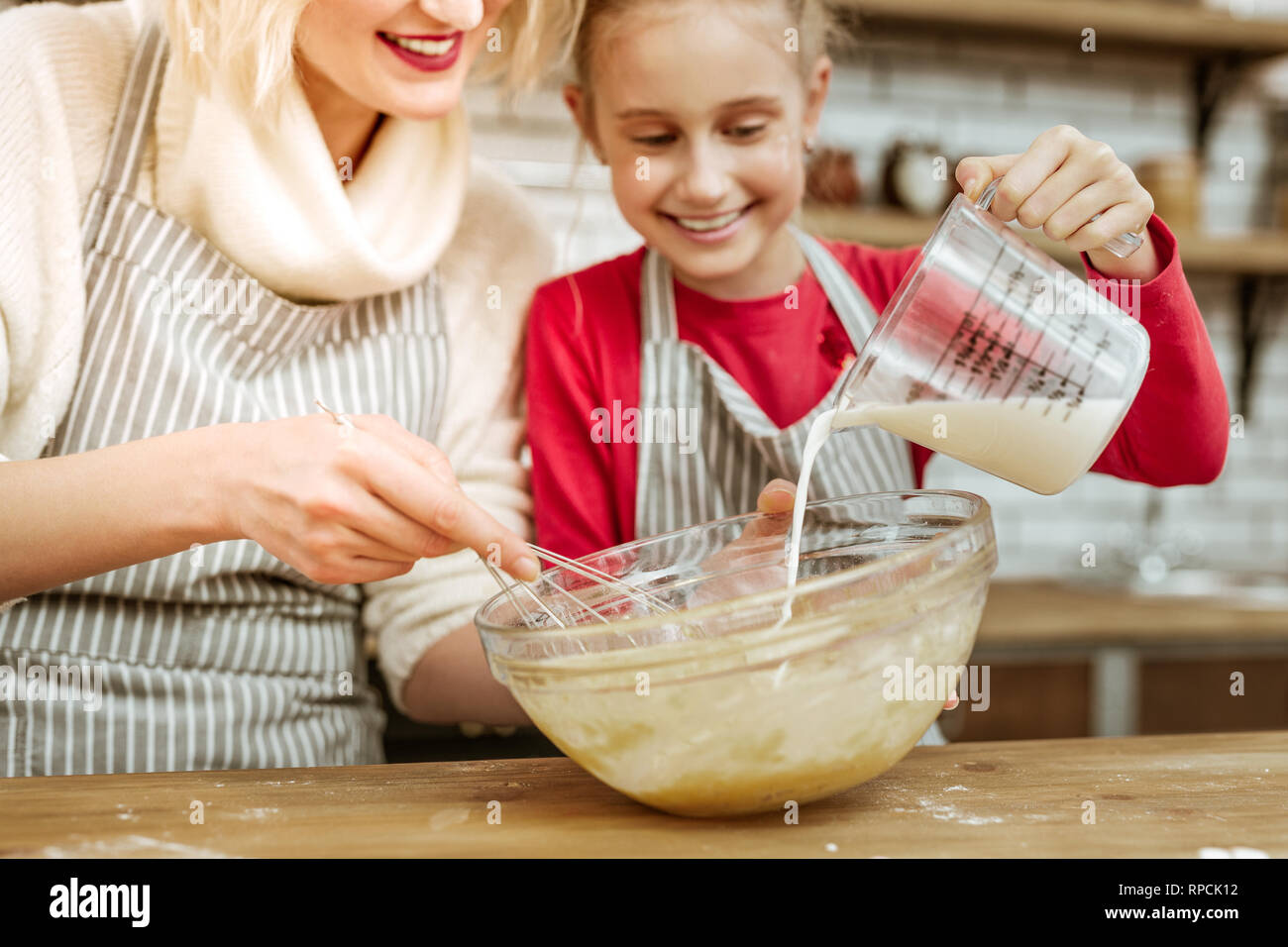 Happy joyful little kid adding milk from measuring cup Stock Photo