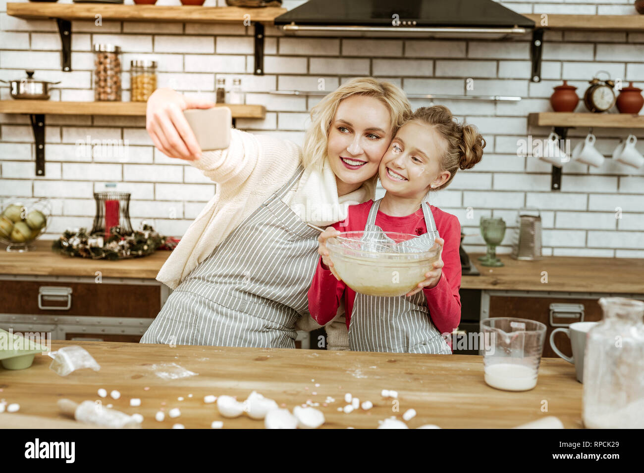 Smiling beaming lady making photo of herself with positive daughter Stock Photo