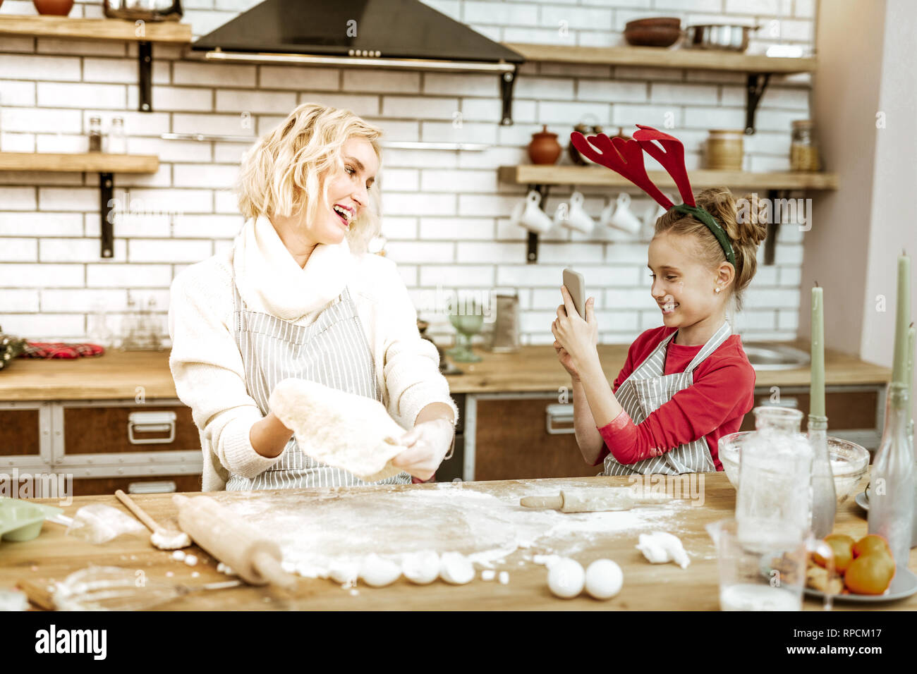 Amused young girl making photo of her mother during working process Stock Photo