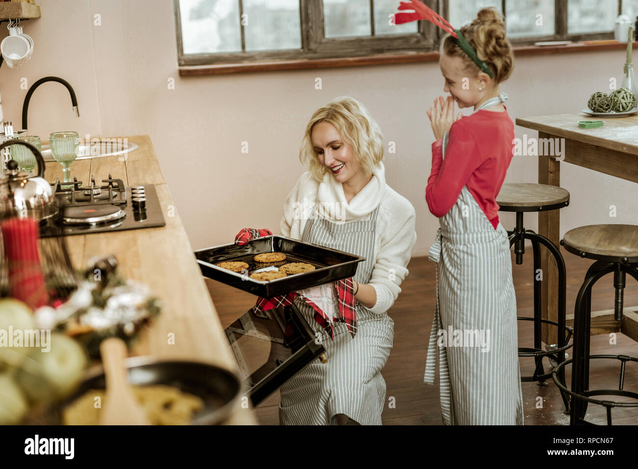 Smiling woman in white sweater controlling her daughter Stock Photo