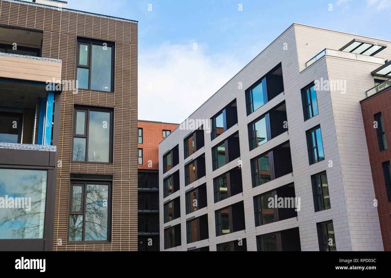 Multi-storey modern house close-up. Brickwork, windows, reflections of sky in glass. Daytime, sun. Modern Apartment Complex Under Construction Stock Photo