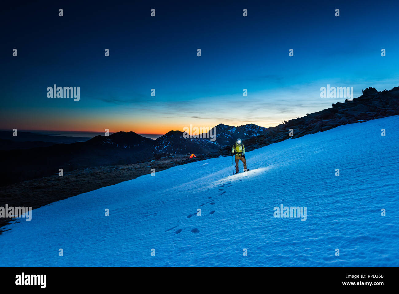 Mountaineer walking on snow with msnowdon in the background Stock Photo