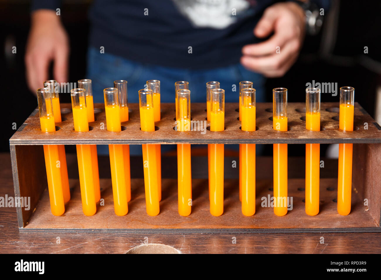 Photo of test tubes with orange liquid and hands of men Stock Photo Alamy