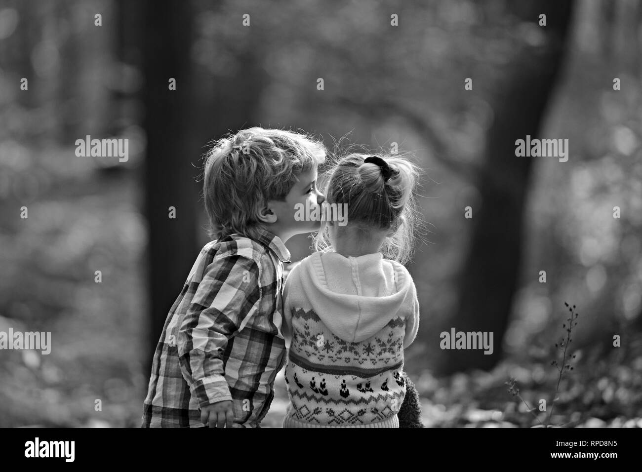 Little boy kiss small girl friend in autumn forest. Brother kiss sister with love in woods. Valentines day concept. Family love and trust. Childhood Stock Photo