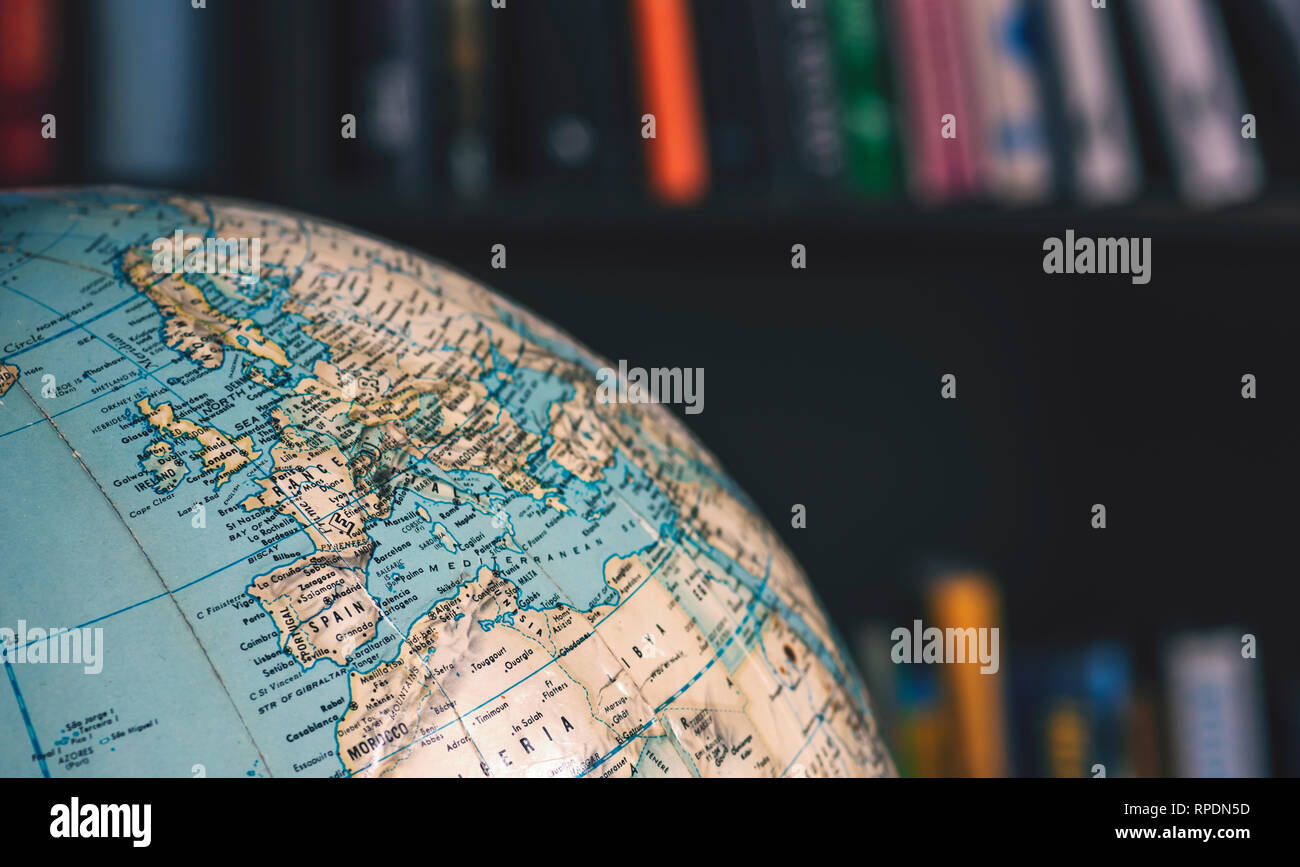 Close up of desktop globe, Europe and Northern Africa. In background out of focus books on shelves Stock Photo
