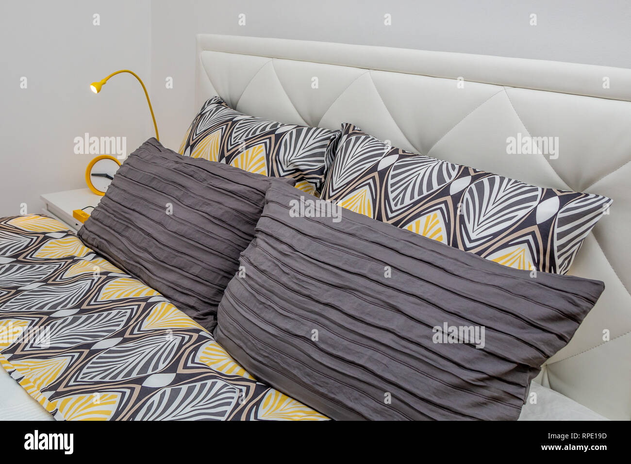 Close up of modern decorative pillows at double bed. Modern hotel bedroom interior. Stock Photo