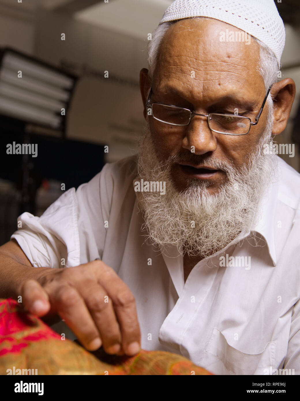 Skilled textiles restorer at the Chhatrapati Shivaji Maharaj Vastu Sangrahalaya museum, Mumbai. Embroidery with gold thread on a Moghal's tunic. Stock Photo