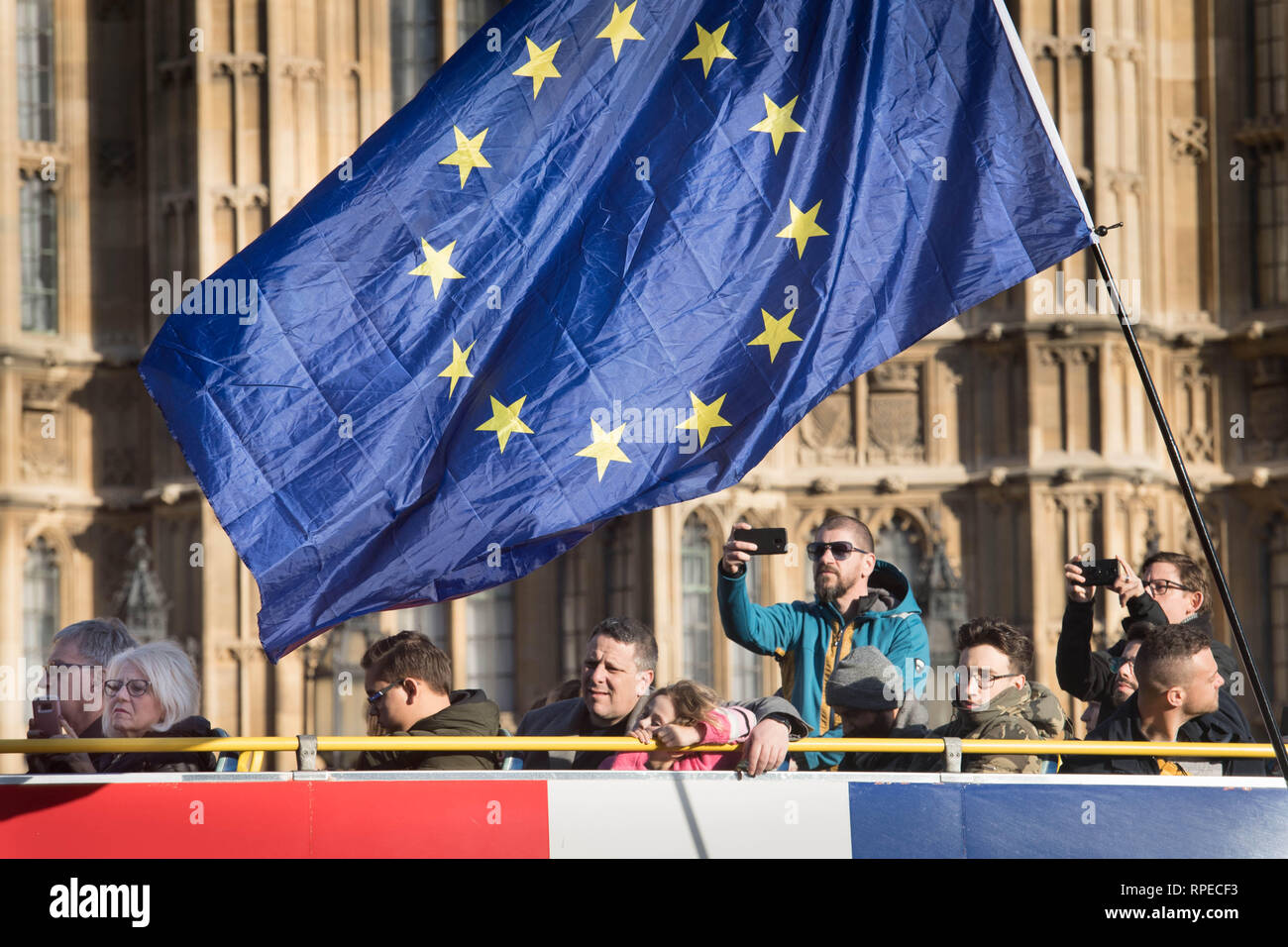 Tourists on an open top bus tour pass by an anti-Brexit demonstration in Westminster. Stock Photo