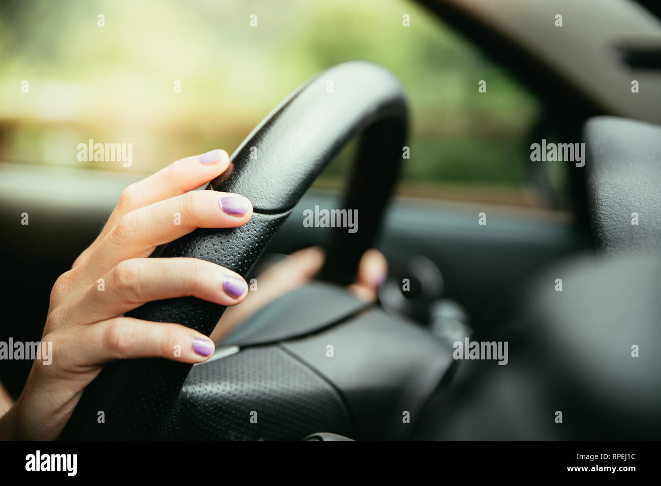 Sports car steering wheel, hands of a young girl with purple nail polish Stock Photo Alamy