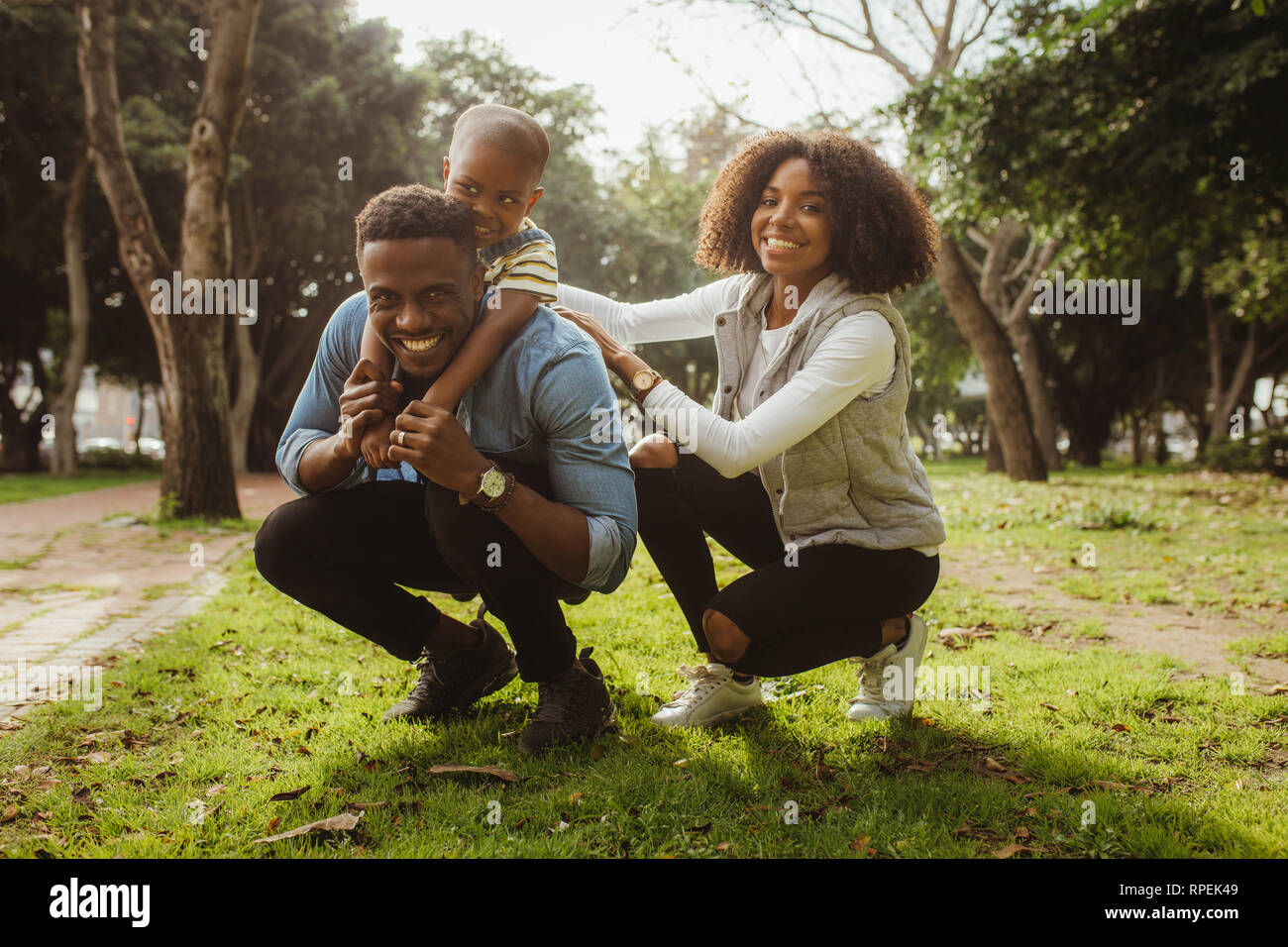 African man carrying his son on his back with woman at park. Happy african family enjoying at the park. Stock Photo