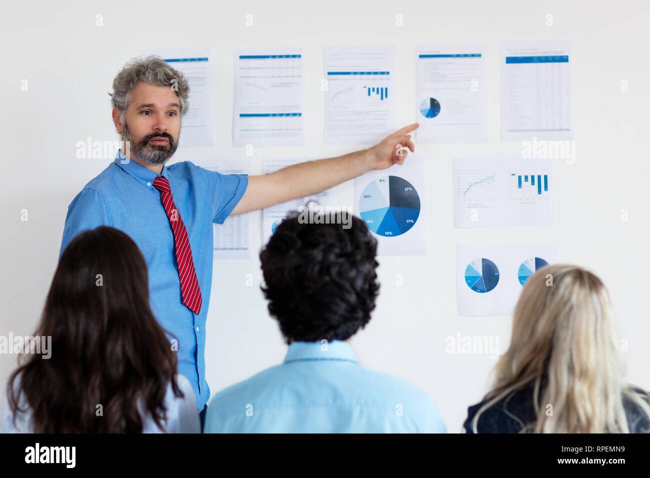 Elderly businessmann with grey hair giving presentation to colleagues at office of modern company Stock Photo