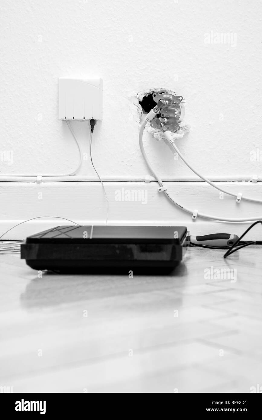 Fiber optic installation at home with obsolete CATV and new FTTH fiber outlets and internet receiver on parquet floor Stock Photo